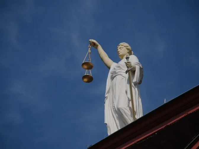 Estátua da Justiça segurando a balança, símbolo do Direito, sobre um céu azul — ilustração do artigo sobre a importância do advogado previdenciário.